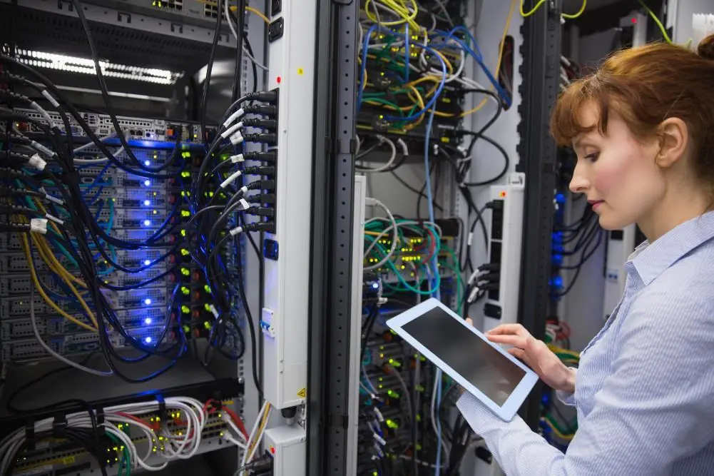 IT specialist using a tablet while inspecting network servers